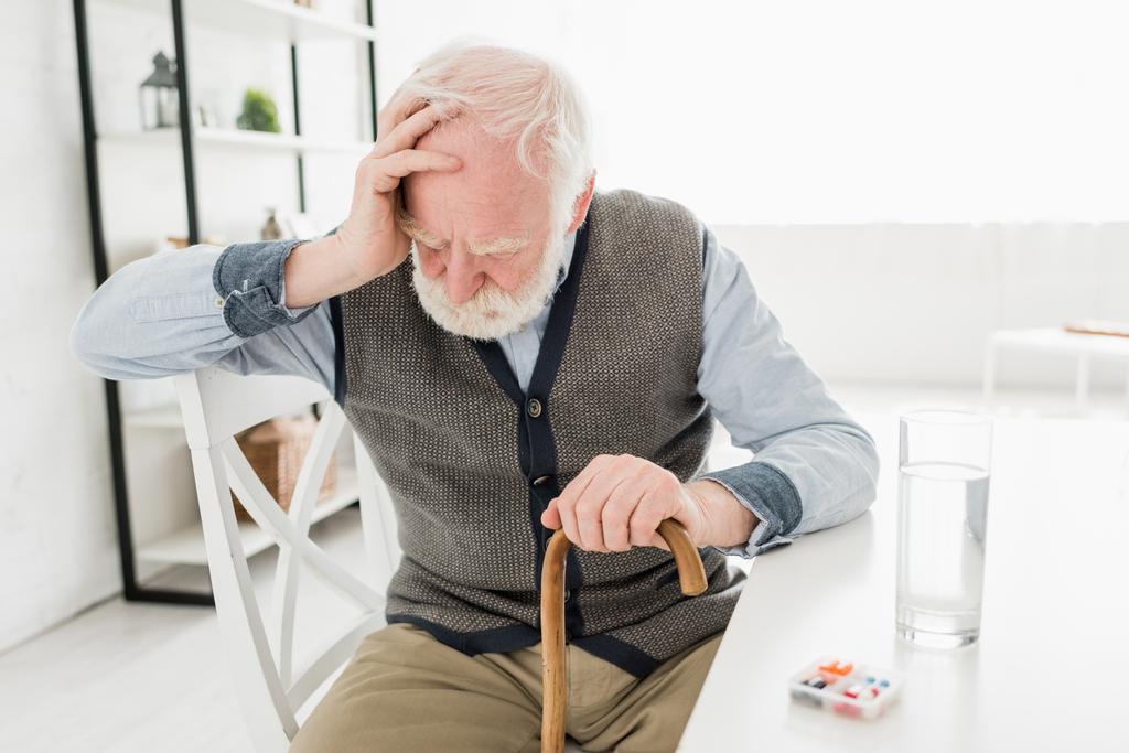 Homem idoso deprimido com bengala, sentado em casa
 - Foto, Imagem
