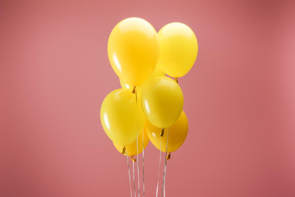 ピンクの背景に黄色の明るいお祝いの風船 - 写真・画像