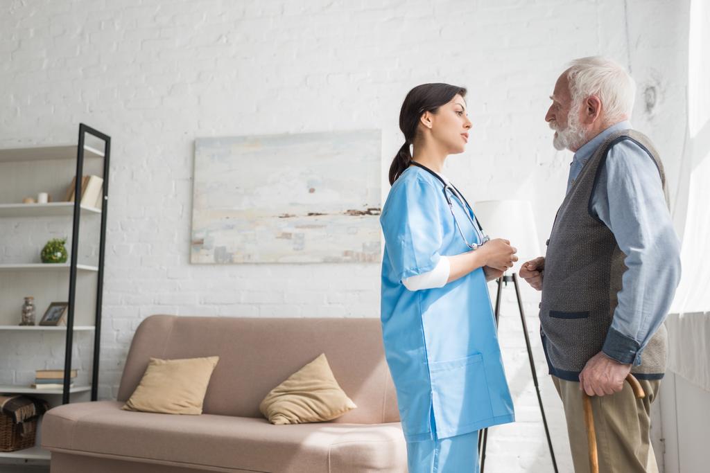 Hombre de pelo gris hablando con la enfermera, de pie en la habitación con espacio para copiar
 - Foto, imagen