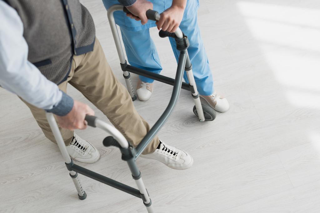 Hoge hoek van de gepensioneerde man wandelen met arts, herstellen na een blessure - Foto, afbeelding