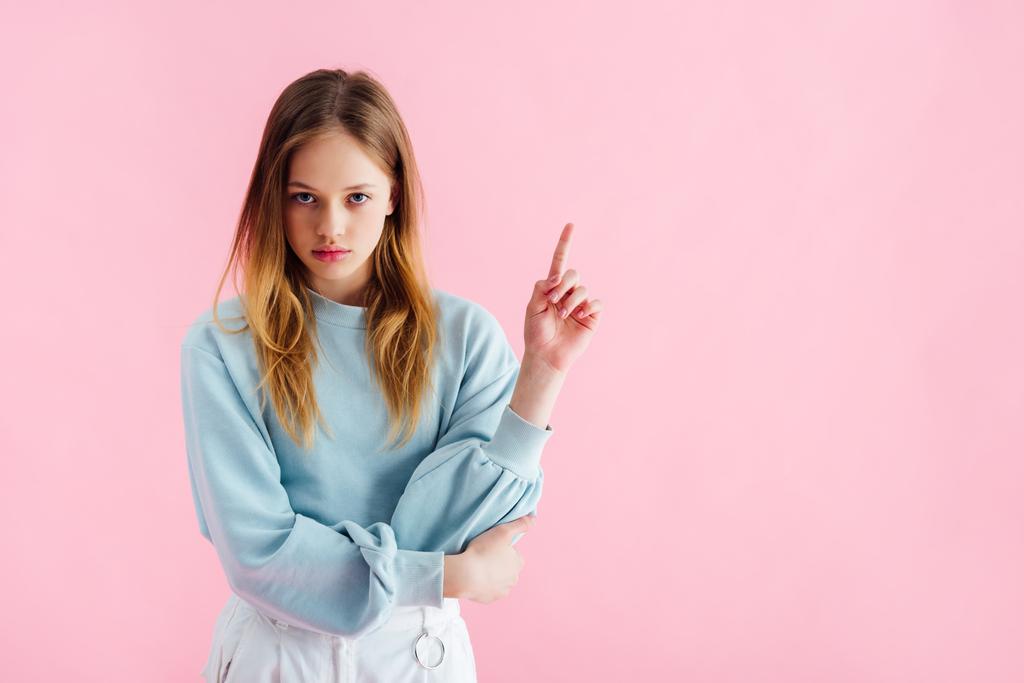 trieste tiener meisje wijzend met de vinger geïsoleerd op roze - Foto, afbeelding