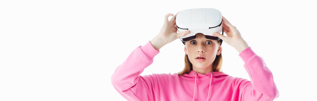 πανοραμική βολή από σοκ έφηβο κορίτσι με ροζ κουκούλα φορώντας ακουστικά VR απομονωμένη σε λευκό - Φωτογραφία, εικόνα