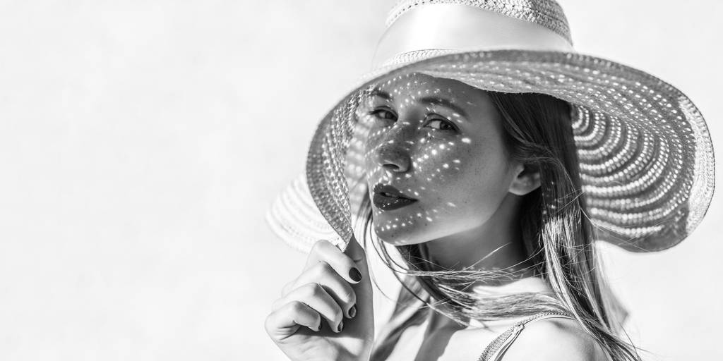 Портрет красивой чувственной брюнетки молодой женщины с макияжем глядя в камеру со страстью и держа шляпу, свет через шляпу падает на лицо
  - Фото, изображение