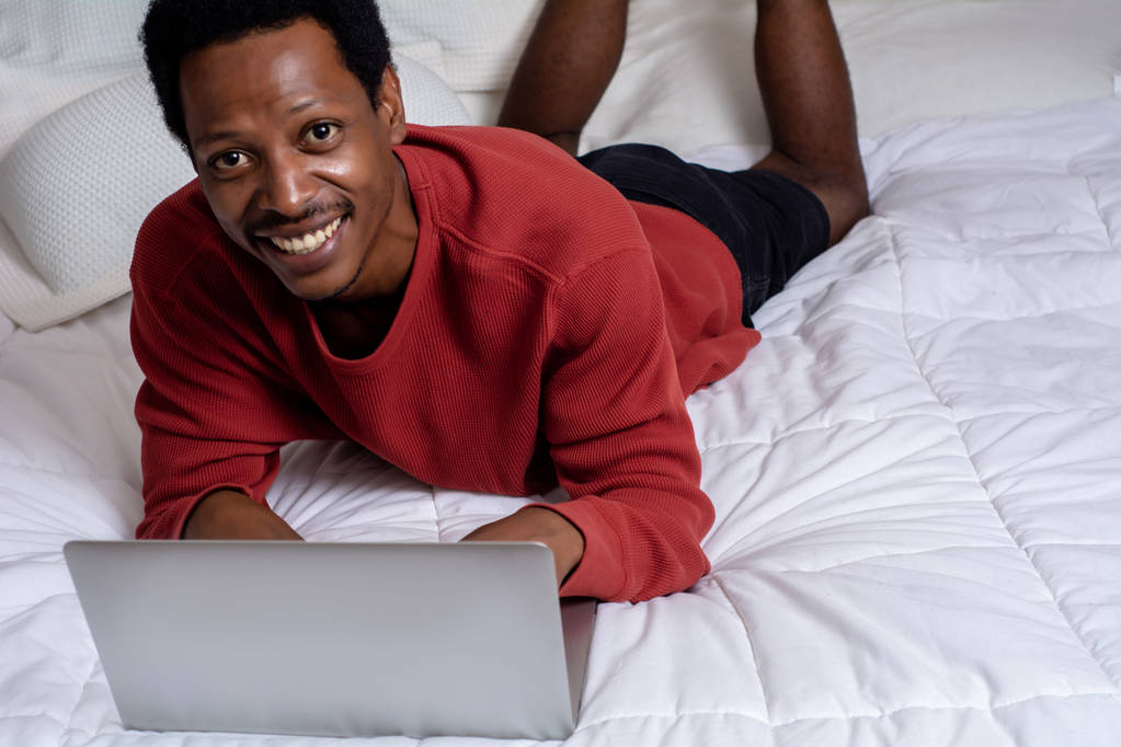 Junger Mann mit Laptop im Bett - Foto, Bild