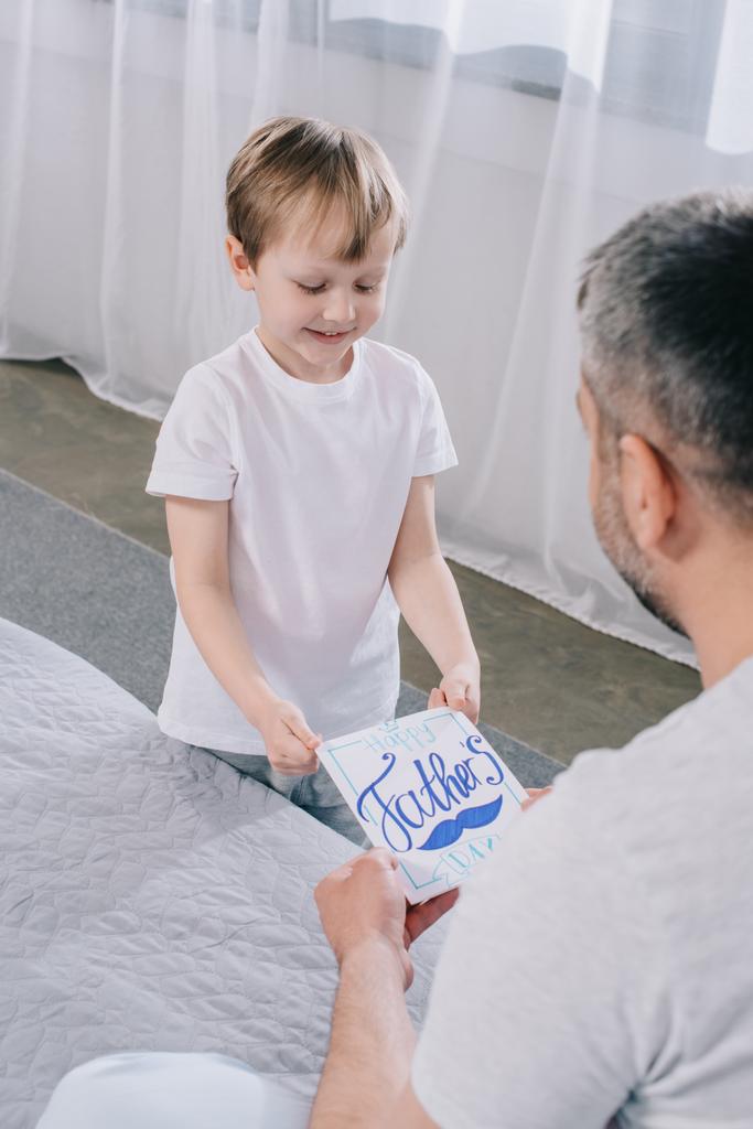 adorable garçon souriant et cadeau carte de voeux de jour de pères à papa
 - Photo, image