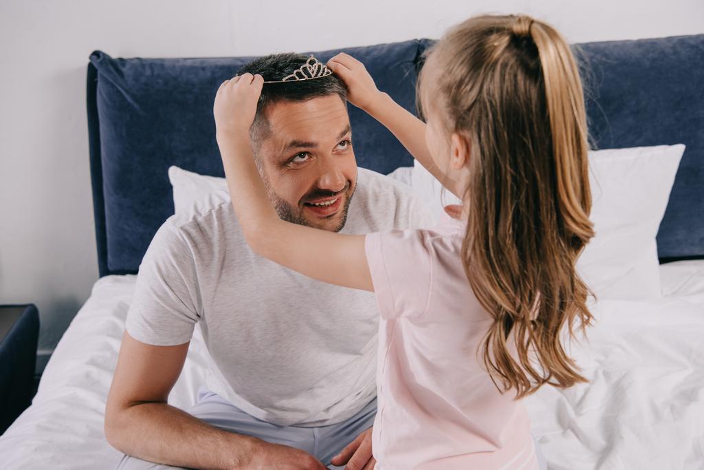 cute daughter putting diadem on happy dad on fathers day - Photo, Image