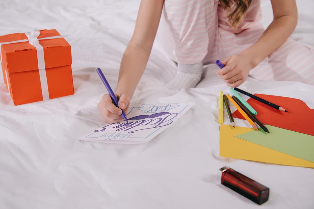 recortado vista de niño dibujo padres día tarjeta de felicitación cerca de la caja de regalo y papel multicolor
 - Foto, Imagen