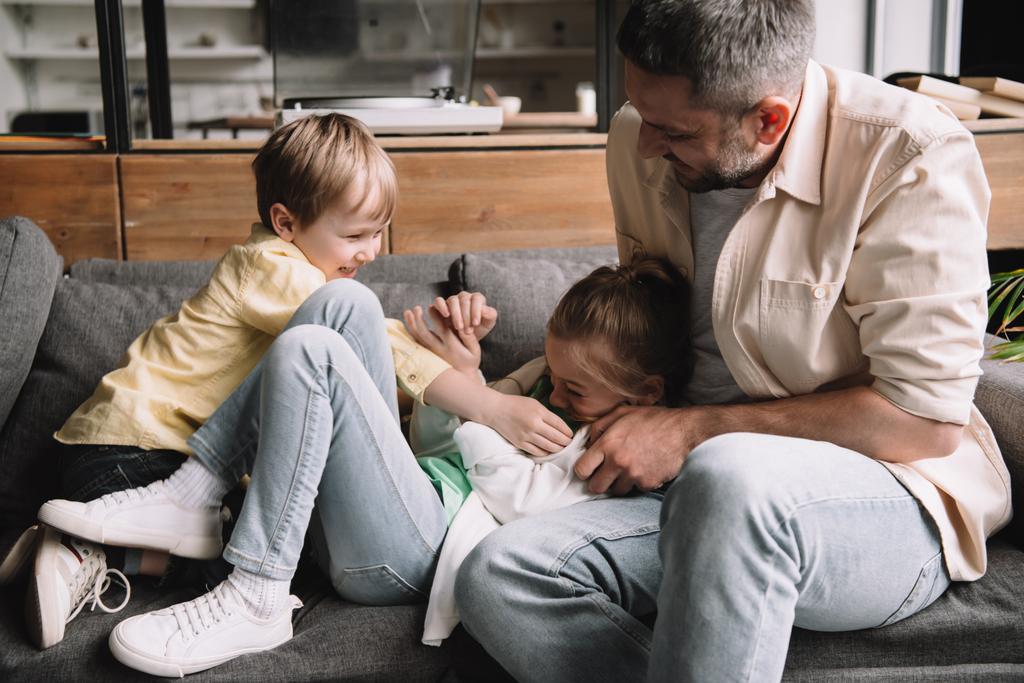 heureux père avec des enfants gais s'amuser le jour des pères sur le canapé à la maison
  - Photo, image