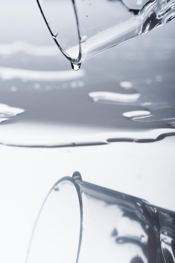 glas met gemorst water en druppels op licht oppervlak - Foto, afbeelding