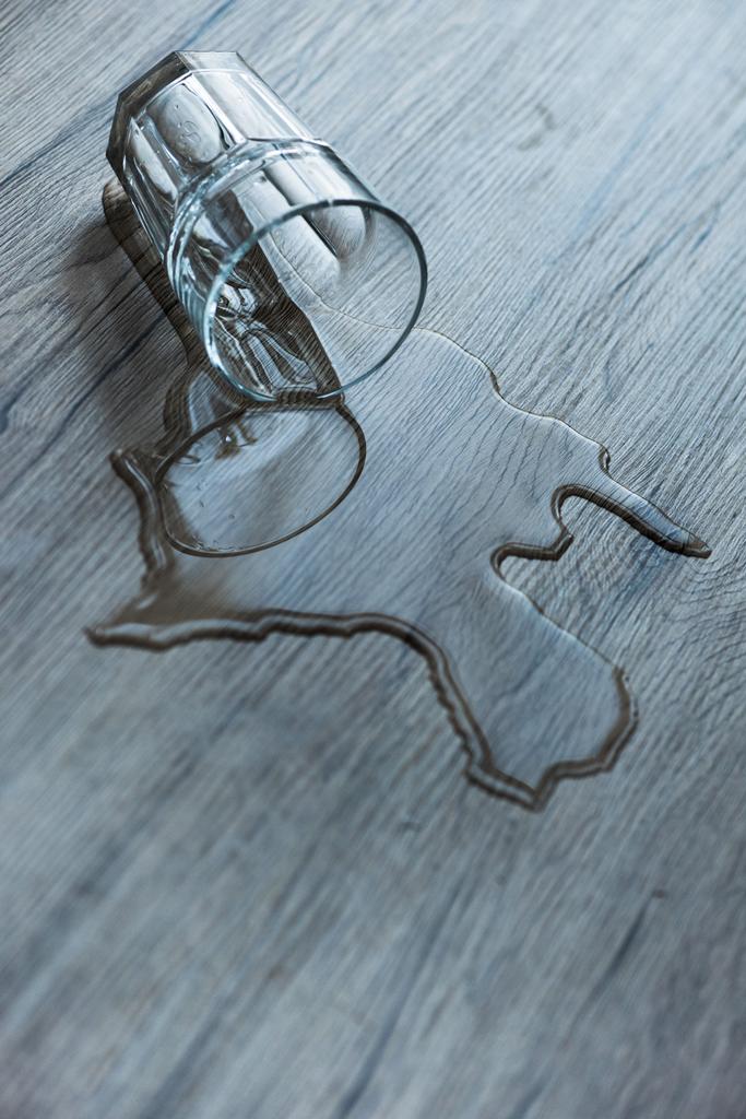 glass with spilled water on textured wooden surface - Photo, Image
