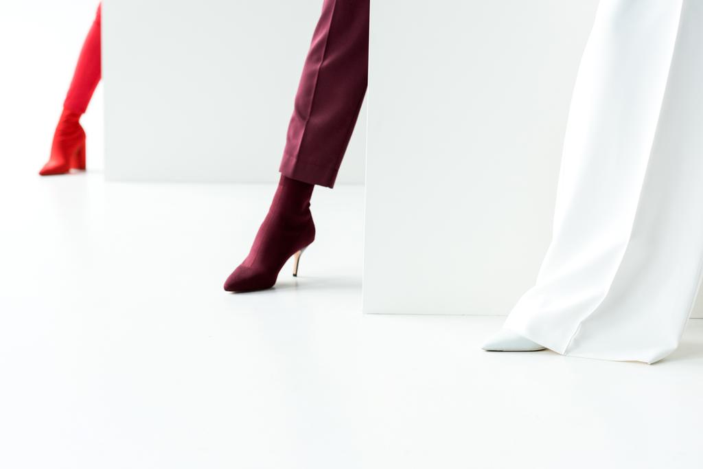oříznutý pohled na stylové ženy stojící v podpatcích na bílém  - Fotografie, Obrázek