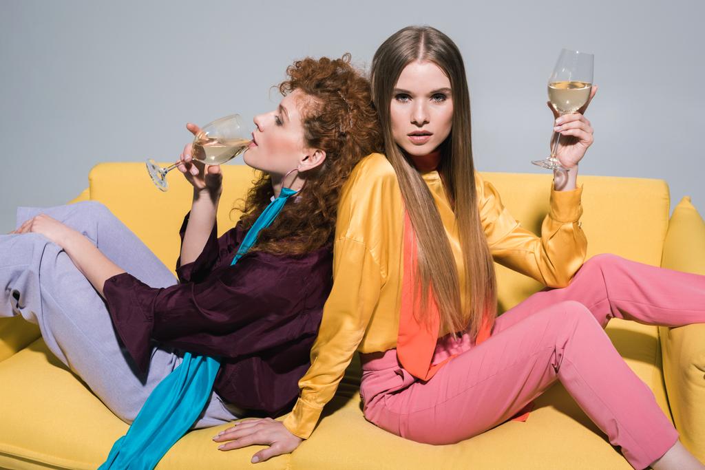 白のブロンドの若い女性の近くにシャンパンを飲む魅力的な赤毛の女の子  - 写真・画像