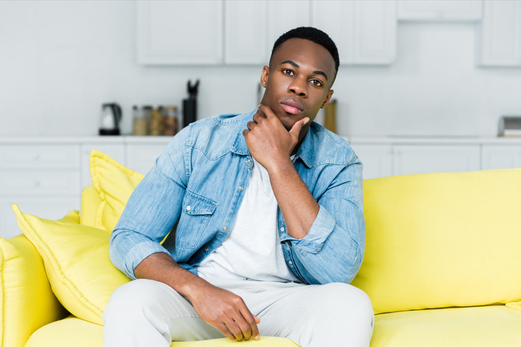 African American man kijkt naar camera, zittend op de Bank - Foto, afbeelding