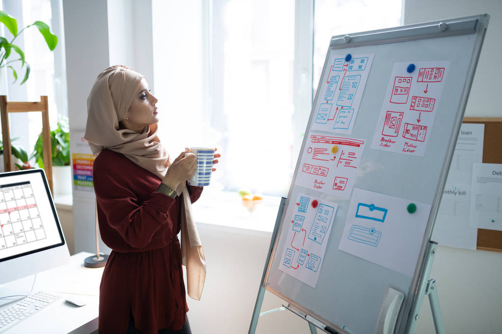 Moslim leraar drinken van thee en staande in de buurt van Whiteboard - Foto, afbeelding