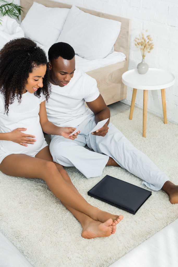 High Angle view van zwangere Afro-Amerikaanse vrouw kijkt naar foto met vriendje - Foto, afbeelding