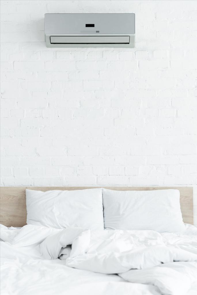 белая спальня с кирпичной стеной, кроватью и кондиционером
 - Фото, изображение