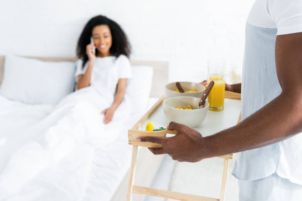 Selektywny fokus African American mężczyzna gospodarstwa spróbować ze śniadaniem, na uśmiechnięta dziewczyna tle - Zdjęcie, obraz