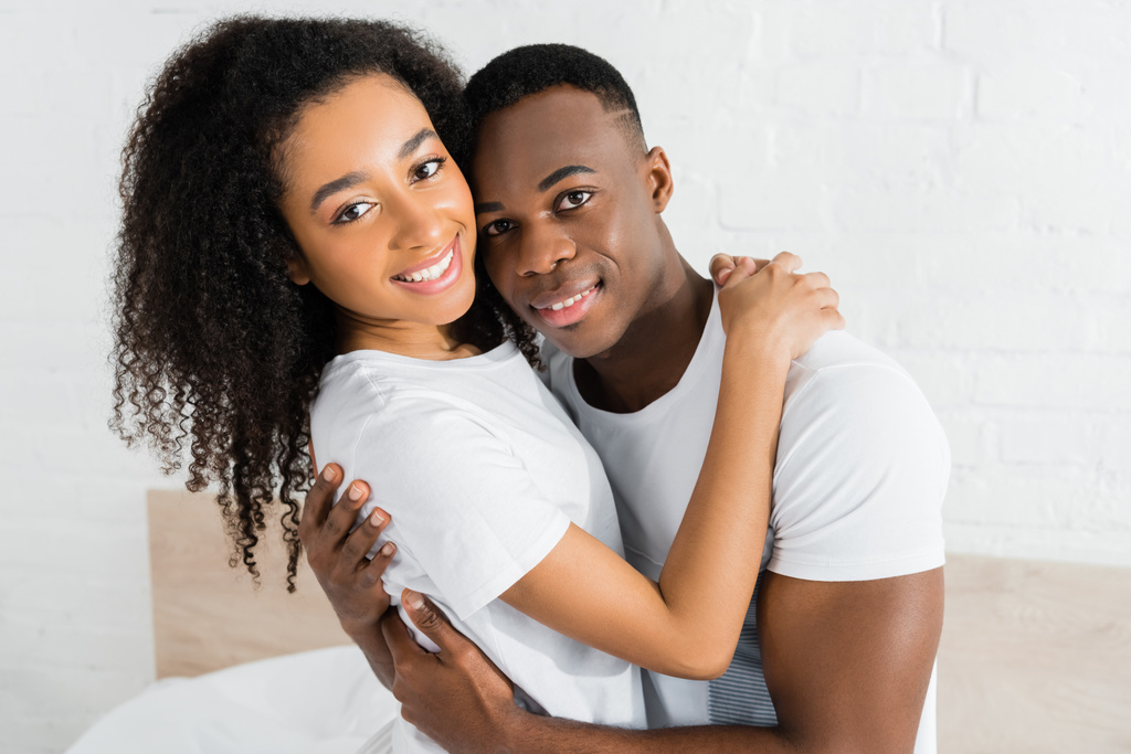 couple afro-américain se serrer dans ses bras et regarder la caméra
 - Photo, image