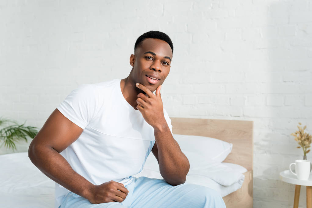 ευτυχισμένος Αφρικανός Αμερικανός άνθρωπος κοιτάζοντας την κάμερα, κάθεται στο σπίτι στο λευκό δωμάτιο - Φωτογραφία, εικόνα