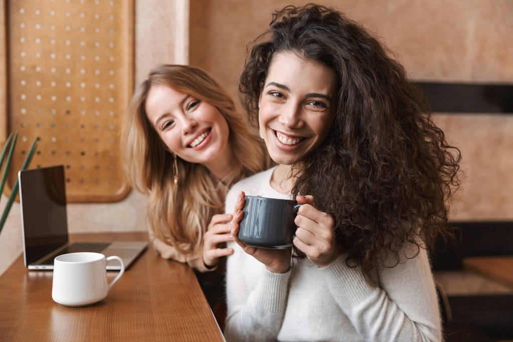 Dos jóvenes novias alegres sentadas en el café
 - Foto, Imagen