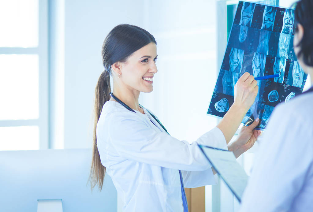 Kaksi hymyilevää lääkäriä osoittamassa röntgenkuvia sairaalassa. - Valokuva, kuva