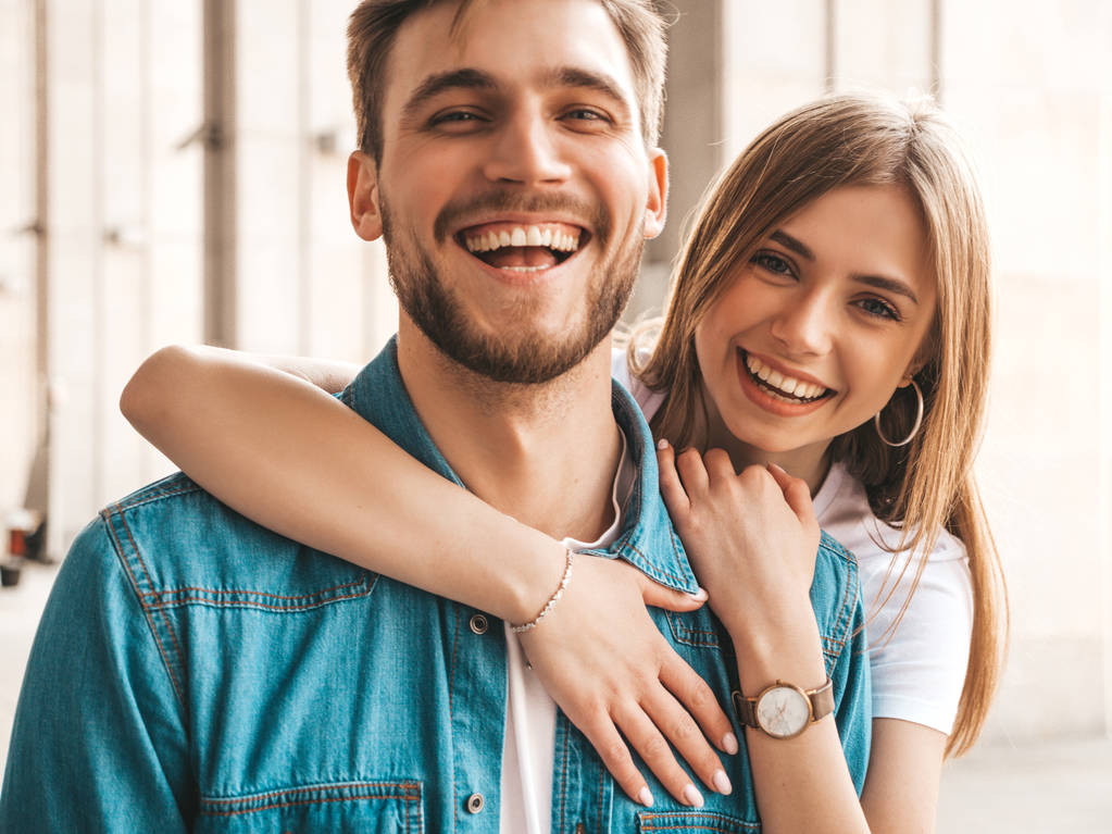 Portret van glimlachend mooi meisje en haar knappe vriendje. Vrouw in Casual zomer jeans kleding. Gelukkig vrolijke familie. Vrouw met plezier op de straat achtergrond. Winking - Foto, afbeelding