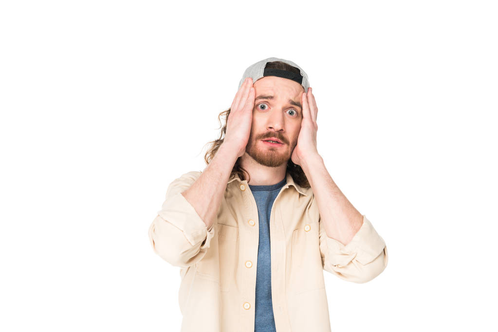 Schockierter junger Mann hält Kopf mit Händen auf weißem Hintergrund - Foto, Bild