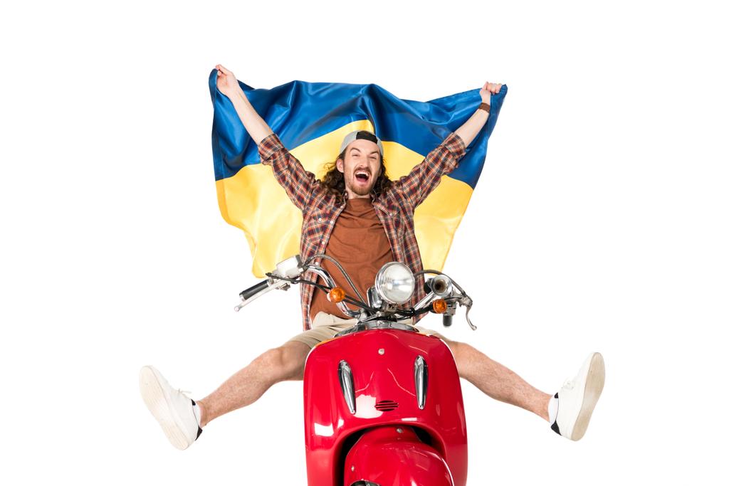 volledige lengte weergave van Happy Young man zittend op rode scooter, het houden van Oekraïense vlag in de lucht geïsoleerd op wit - Foto, afbeelding