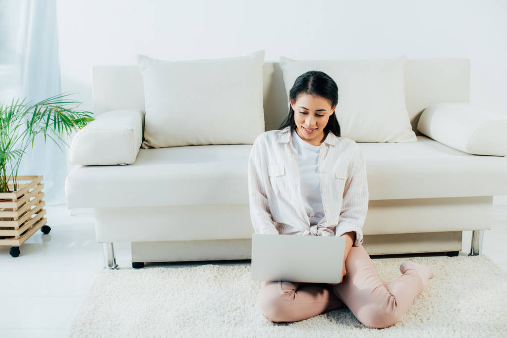 jovem mulher latina usando laptop enquanto sentado no chão perto do sofá
 - Foto, Imagem