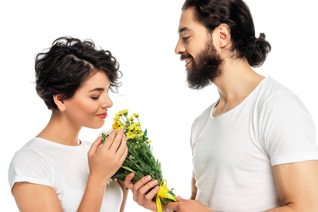 brunette latin woman smelling flowers near handsome man isolated on white  - Photo, Image