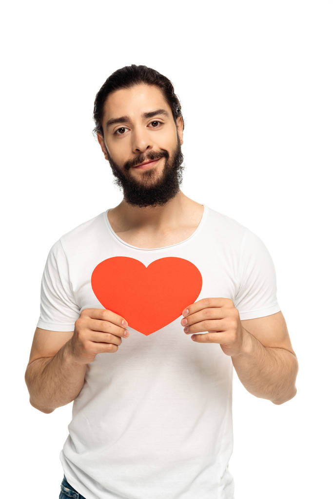 fröhlicher lateinischer Mann mit rotem Karton in Herzform, isoliert auf weißem Papier  - Foto, Bild