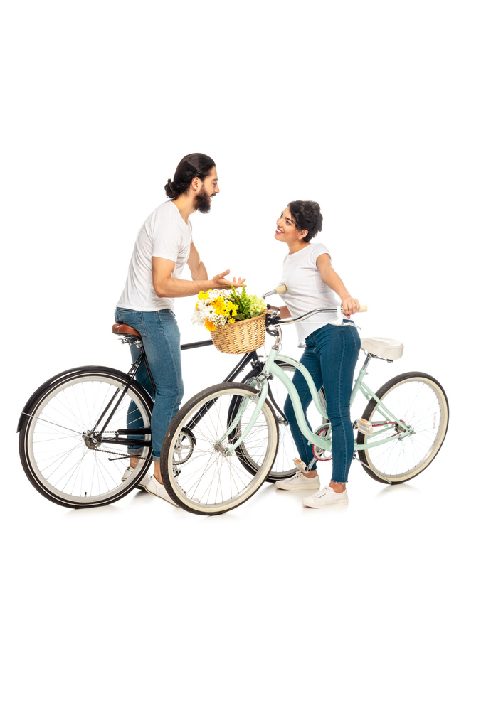 szczęśliwy łaciński człowiek rozmawia z atrakcyjną brunetką i stoi w pobliżu roweru na białym tle  - Zdjęcie, obraz