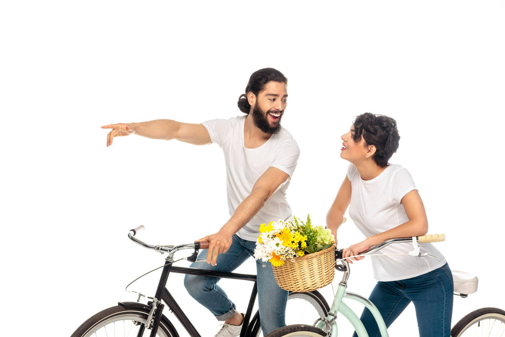 beyaz izole çekici kadın yakınında bisiklet sürerken parmak ile işaret mutlu latin adam  - Fotoğraf, Görsel
