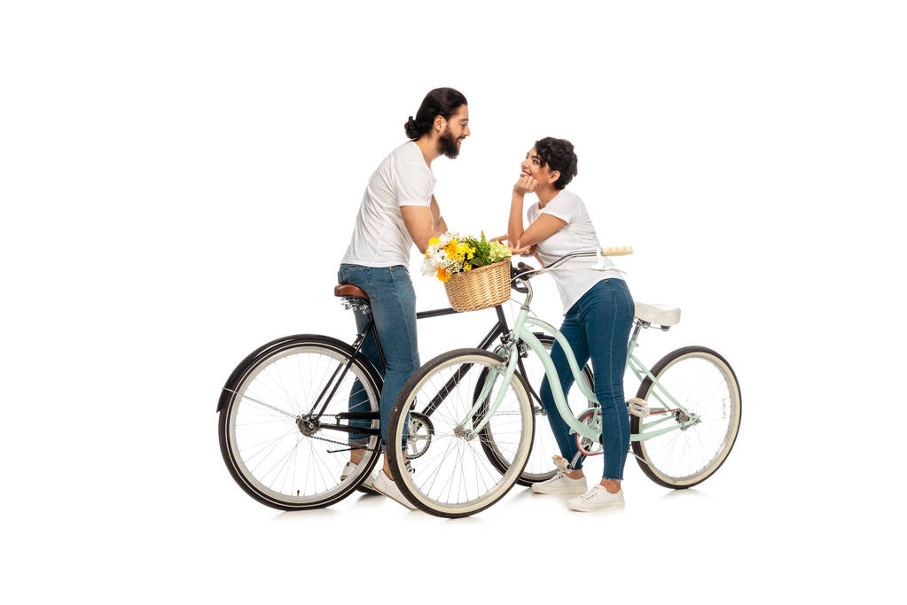 bärtiger lateinischer Mann sieht attraktive Frau auf Fahrrad sitzend isoliert auf weißem Grund an  - Foto, Bild