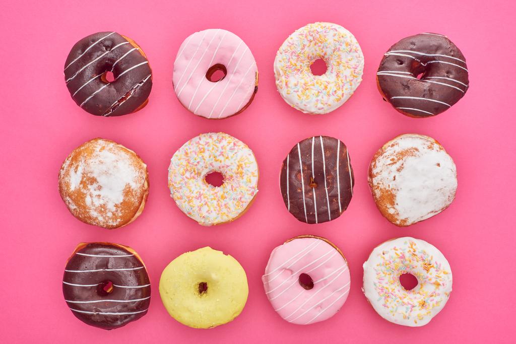 Draufsicht auf leckere glasierte Donuts auf rosa Hintergrund - Foto, Bild