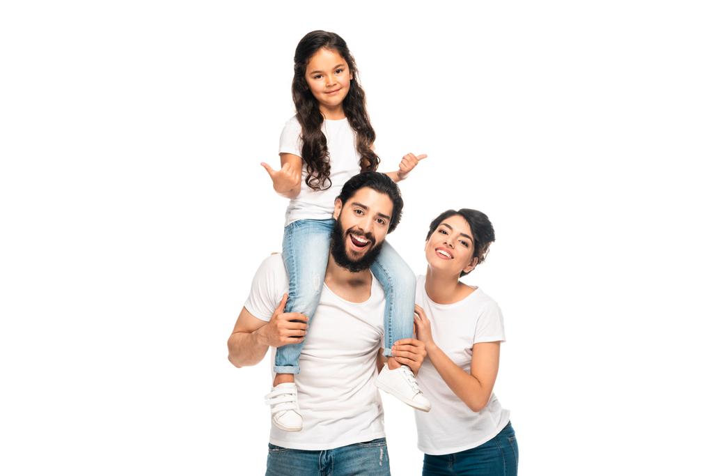 felice latino padre portando sulle spalle carino figlia mostrando pollici verso l'alto vicino felice moglie isolato su bianco
  - Foto, immagini