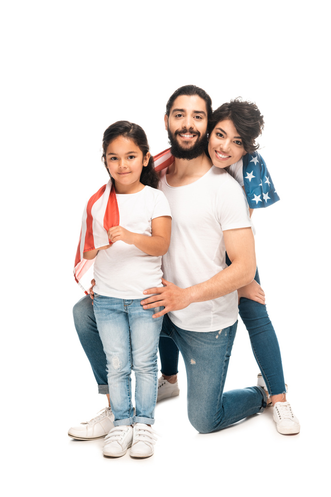 χαρούμενη Λατινική οικογένεια χαμογελά ενώ κρατά αμερικανική σημαία απομονωθεί σε λευκό  - Φωτογραφία, εικόνα