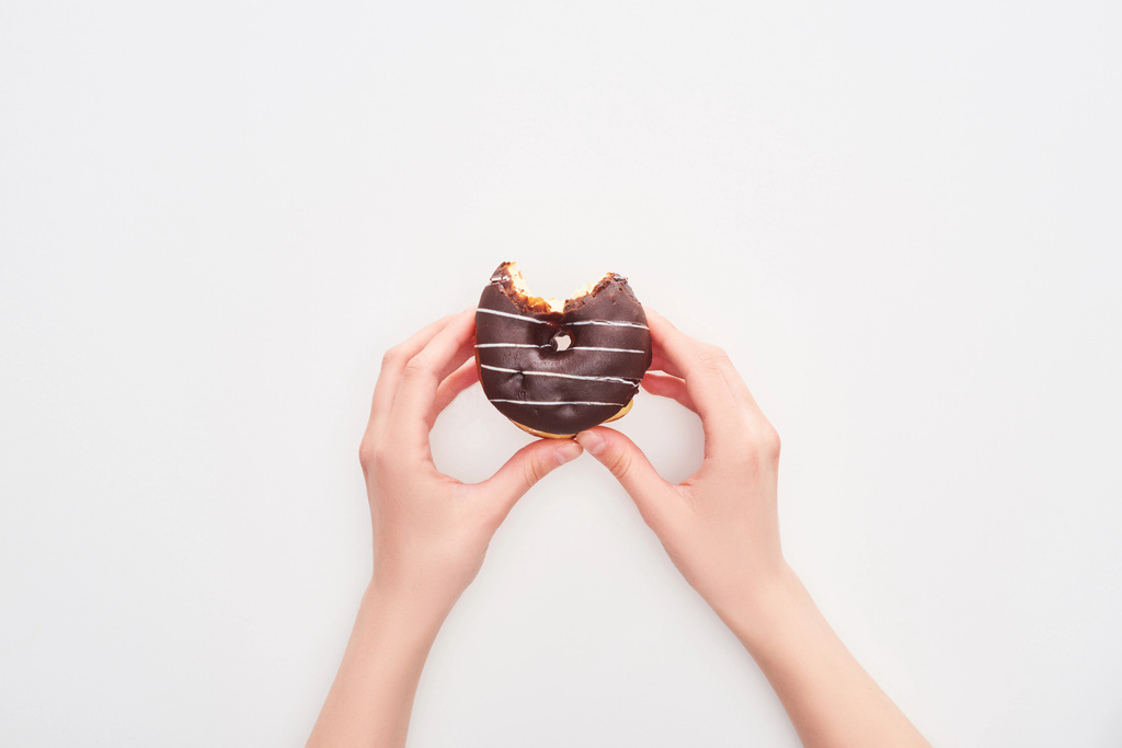 vue recadrée de la femme tenant savoureux beignet au chocolat glacé mordu sur fond blanc
 - Photo, image