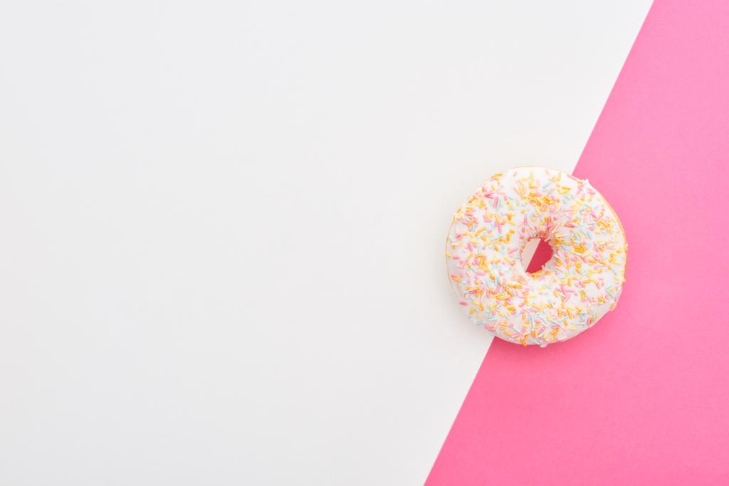 вид зверху глазурованого білого пончика зі зморшками на білому і рожевому фоні з копією простору
 - Фото, зображення
