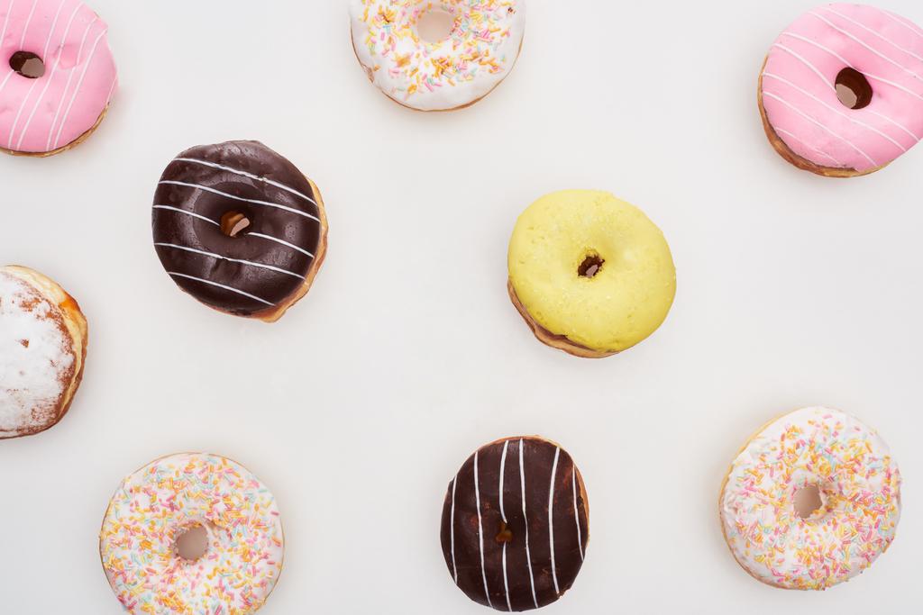 вид сверху на красочные глазурованные вкусные пончики на белом фоне
 - Фото, изображение