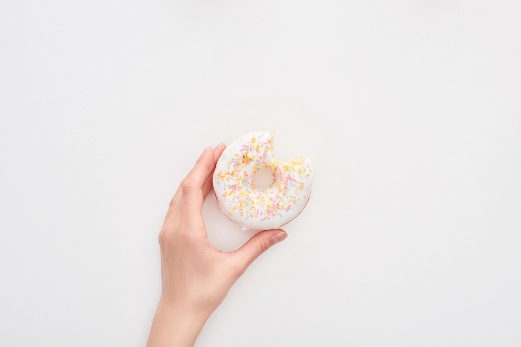 частковий вид жінки, що тримає глазурований білий пончик зі зморшками на білому тлі
 - Фото, зображення