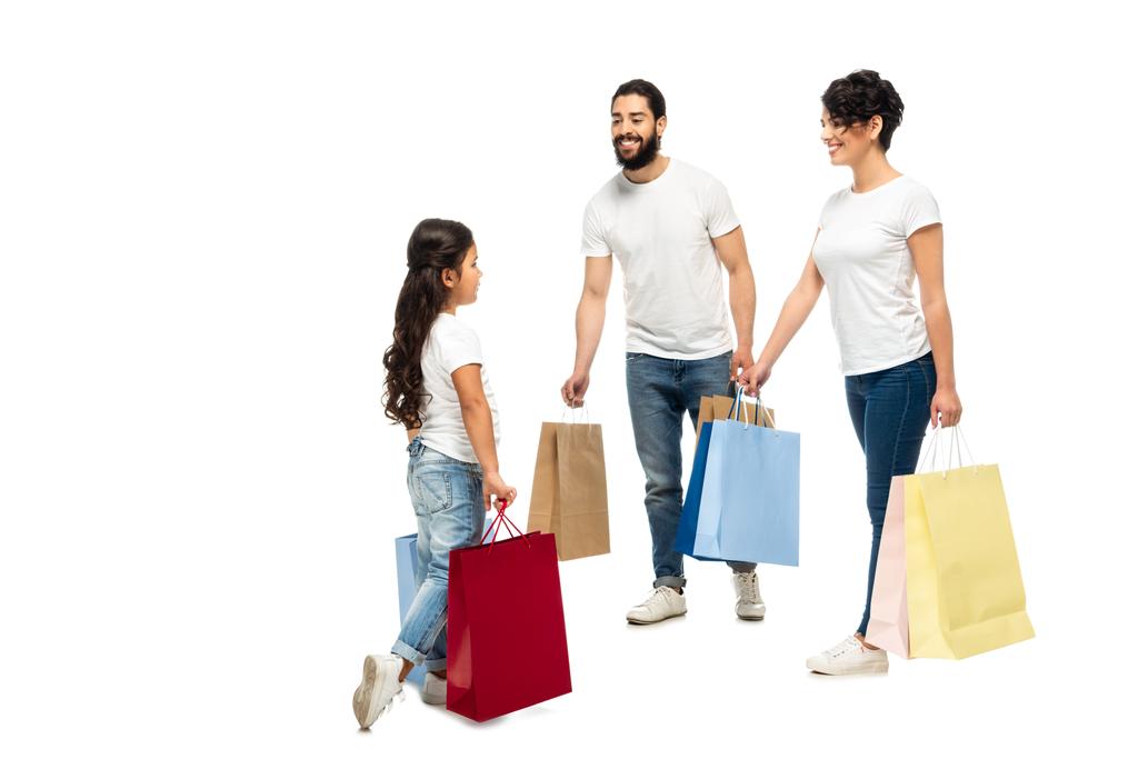 白で孤立した娘を見ながら買い物袋を持っている幸せなラテンの両親   - 写真・画像