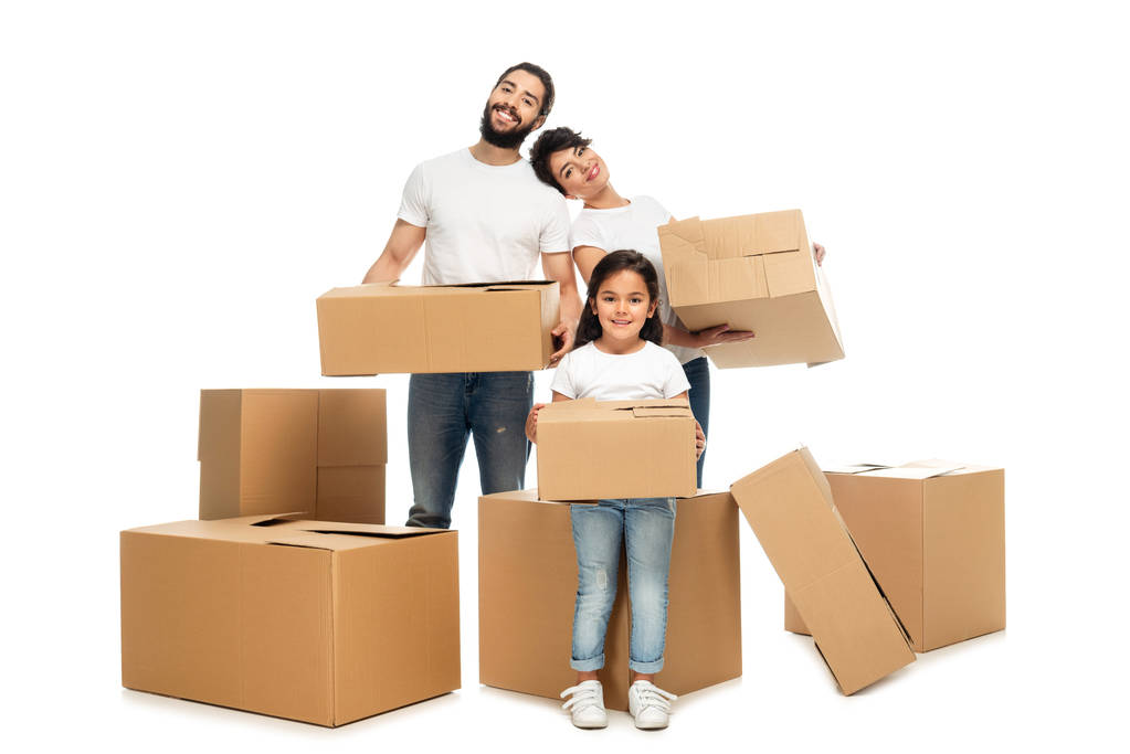 веселі латинські батьки тримають коробки і стоять біля милої дочки ізольовані на білому
  - Фото, зображення