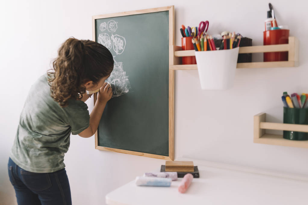 klein meisje tekenen op een schoolbord thuis - Foto, afbeelding