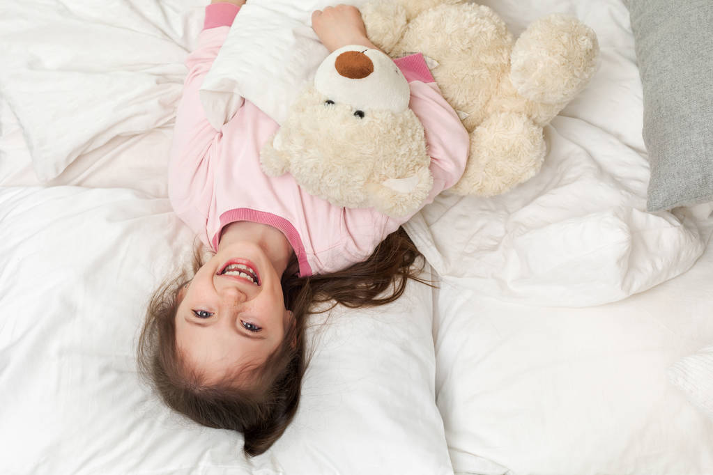 мила маленька дівчинка в піжамах з плюшевим ведмедем
 - Фото, зображення