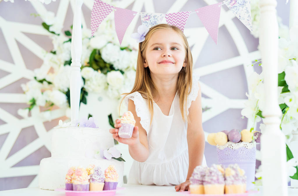 Linda menina loira de pé na bela barra de doces decorados
 - Foto, Imagem