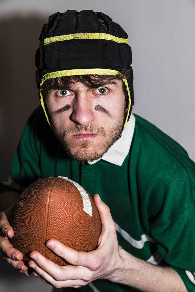 Jugador de rugby sosteniendo la pelota en la mano y haciendo caras
 - Foto, Imagen