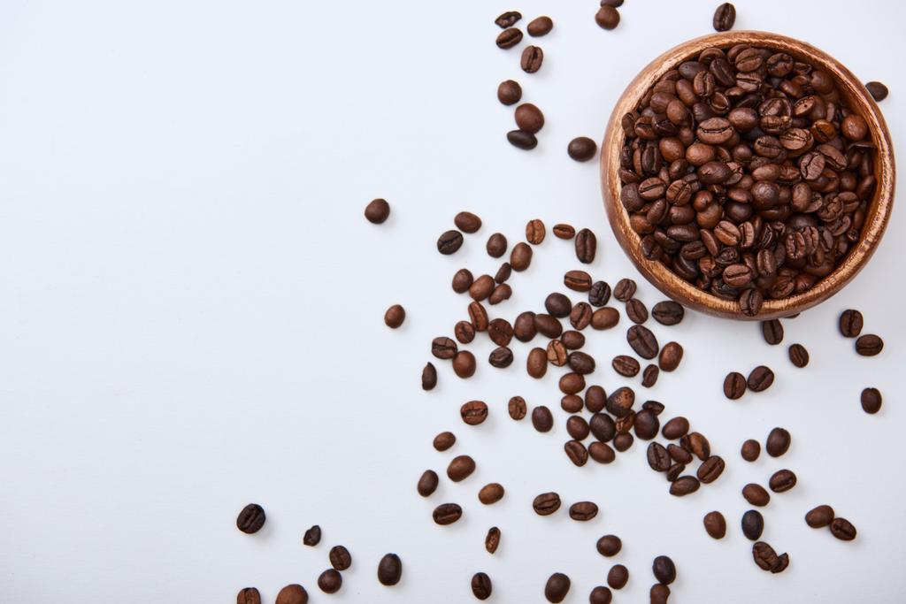 pohled na kávu pečené fazole v dřevěné misce na bílém pozadí - Fotografie, Obrázek