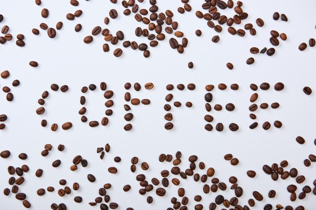 вид зверху на кавове написання з коричневих кавових зерен на білому тлі
 - Фото, зображення