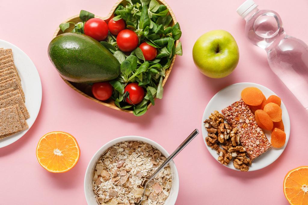 bovenaanzicht van vers dieet voedsel en water op roze achtergrond - Foto, afbeelding